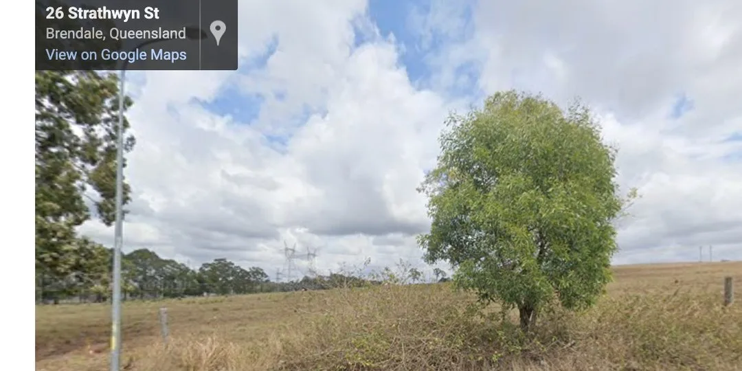 Google Street View of an empty grassed paddock at Brendale in the City of Moreton Bay, with high-voltage transmission towers running along the horizon.